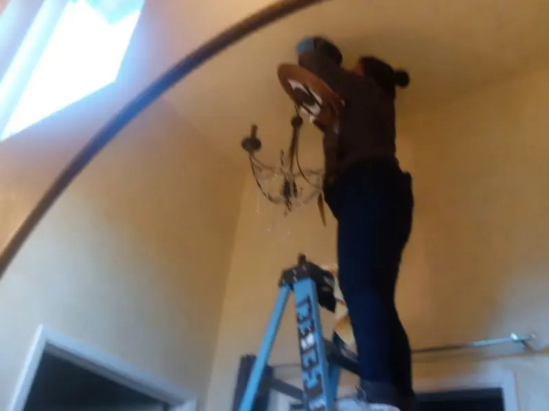 Electrician installing a chandelier in a Maryville residence